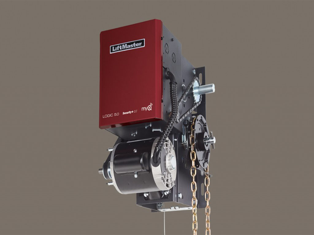 A LiftMaster jackshaft garage door opener with a red and black casing labeled 'Logic 5.0' and 'myQ Security+ 2.0'. The opener is mounted on a black metal bracket and features a side-mounted motor with a chain and sprocket system. A gold-colored manual chain hangs from the unit for emergency operation. The background is a neutral gray color.