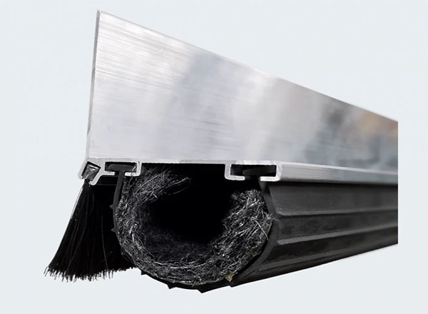 A close-up view of a garage door bottom seal with an aluminum retainer and a thick rubber weatherproofing insert.