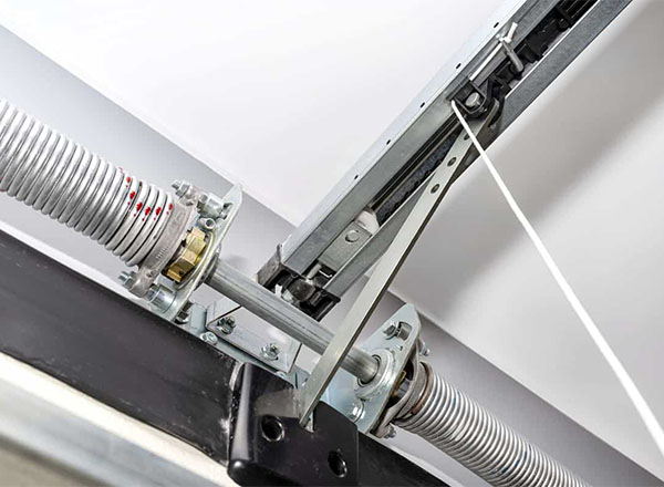 Close-up view of garage door torsion springs, shaft, and opener mechanism.