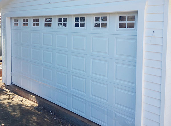 A white garage door with multiple square panels and small windows at the top.